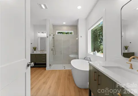 A glass-enclosed shower with a handheld showerhead adds comfort and convenience to the adjoining bath.