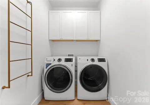 The laundry room pairs a side-by-side washer and dryer with overhead cabinetry for convenient storage.