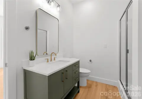 An olive-green vanity and brass fixtures add warmth to this bright bathroom.
