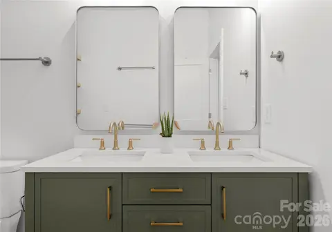 Two sinks, brass fixtures, and olive-green cabinetry create a refined space with room to get ready.