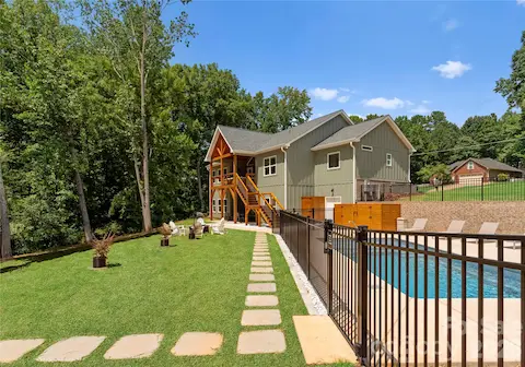 A broad lawn and fenced pool provide room to swim, play, and gather, with the wooded shoreline just beyond.