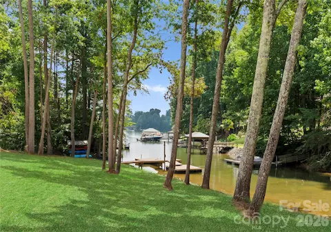 Mature trees frame the lawn and dock, creating a peaceful connection between the home and the water.